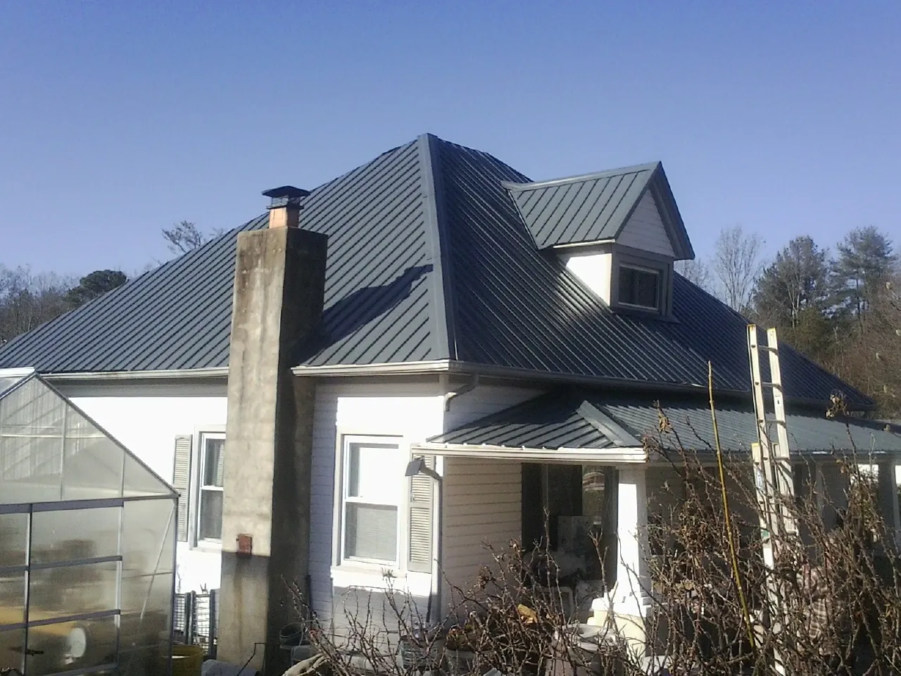 Dark blue standing seam metal roof on a white farmhouse with dormer — Slate & Tile Roof Repair by Roofing Brothers in Brielle