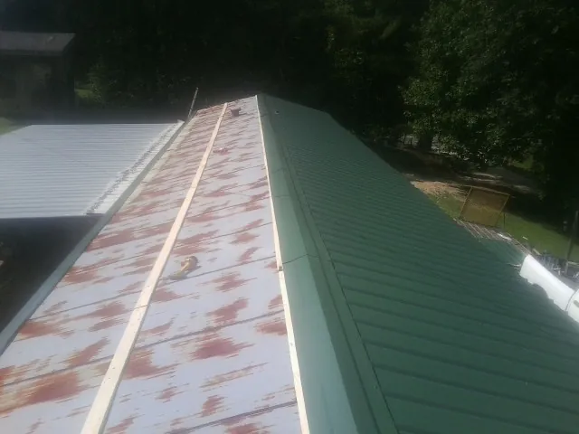 Old rusted panels beside newly installed green metal roofing — Wind Damage Roof Repair by Roofing Brothers in Brielle