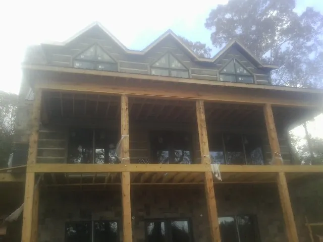 Dormers and porch framing on a large log home under construction — Roof Coating work by our crew in Brielle