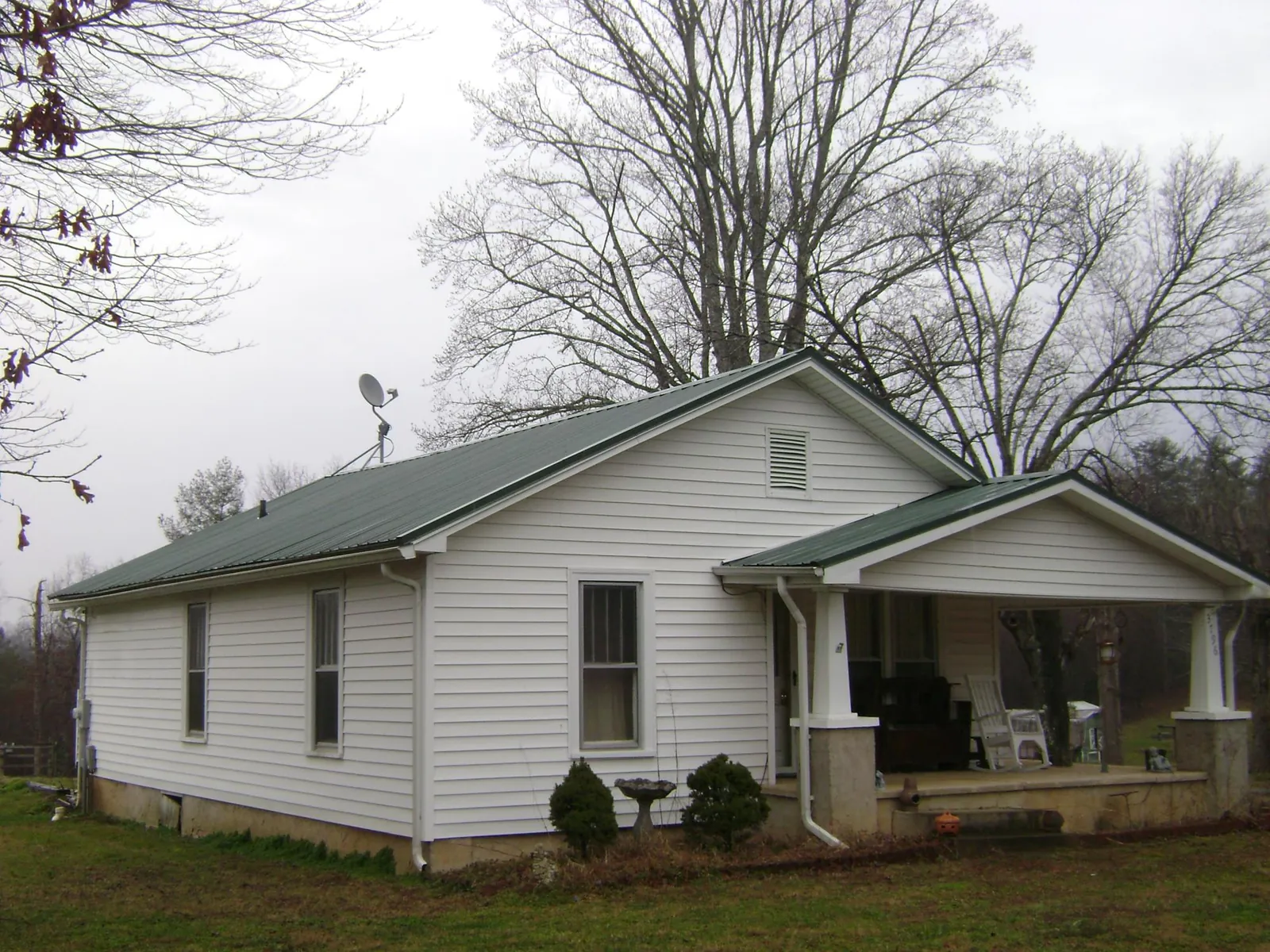 Green metal roof on a white bungalow with a side porch in Brielle