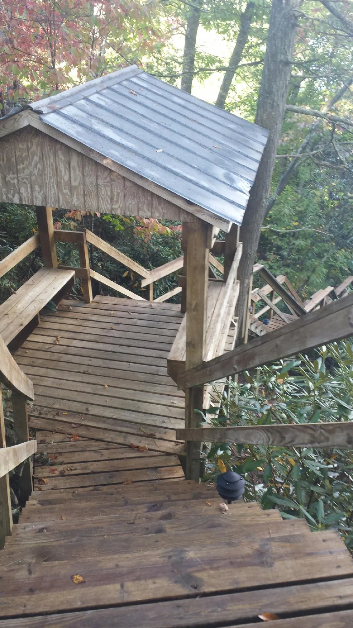 Metal roofed shelter over wooden steps on a wooded walkway — Skylight Repair & Installation work by our crew in Brielle