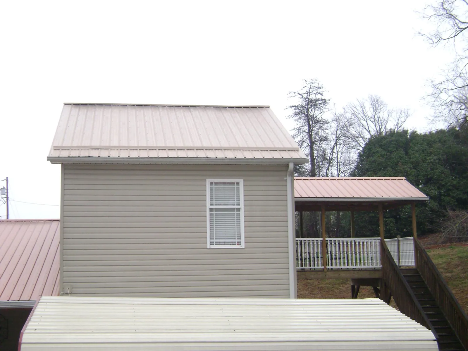 Tan metal roofs on a two story addition and attached porch, from a Roof Replacement job in Brielle