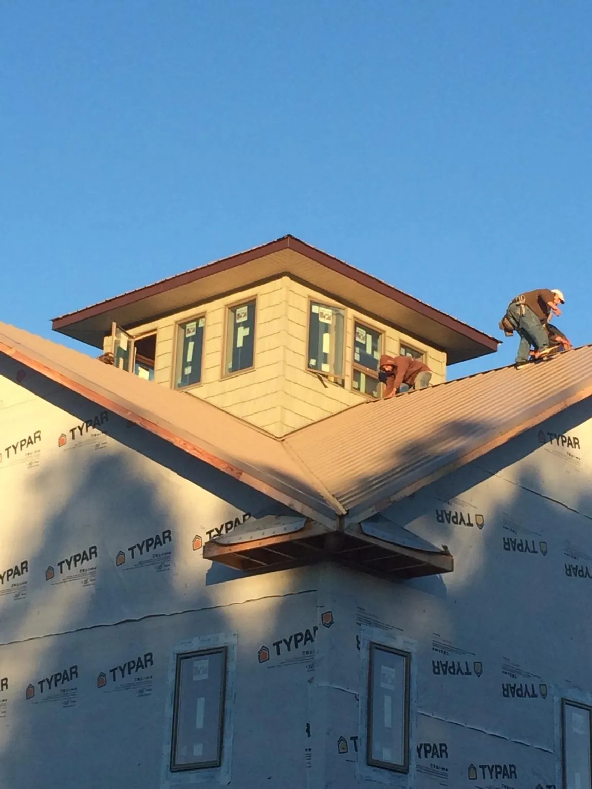 Roofers working around a rooftop cupola on a new metal roof at sunset — Roof Waterproofing in Brielle by Roofing Brothers